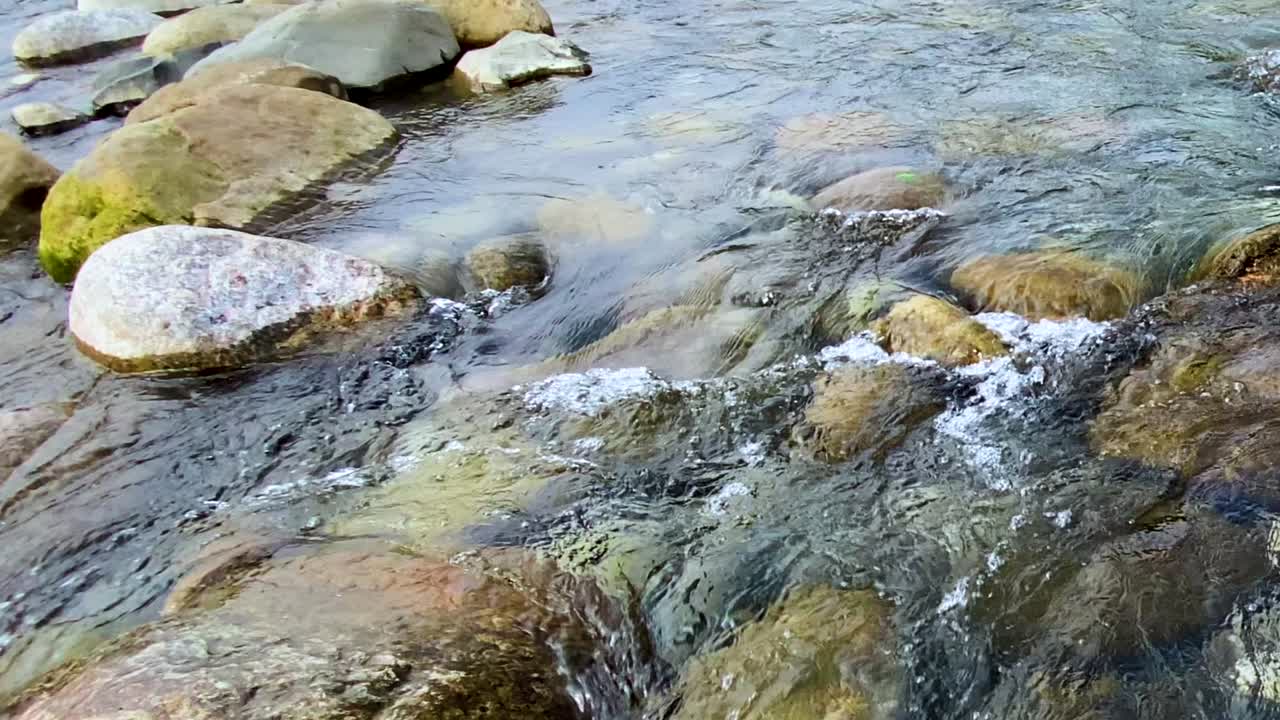 Primo piano dettagliato di acqua dolce che scorre sulle rocce in un ruscello naturale di montagna