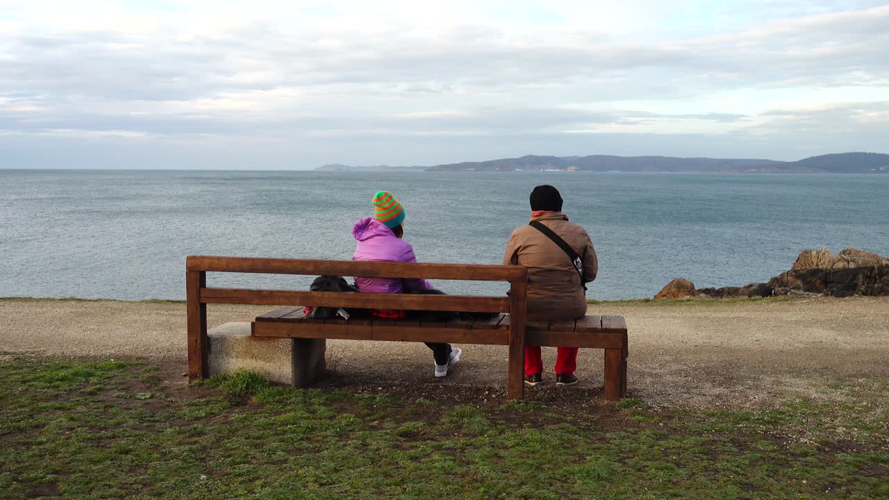 Lidé se dívají na Atlantský oceán z hory. Park menhirů na Campo de la Rata. La Coruña, Španělsko
