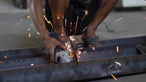 workers are cutting iron using a hand grinder, sparks from the grinder are splattering everywhere