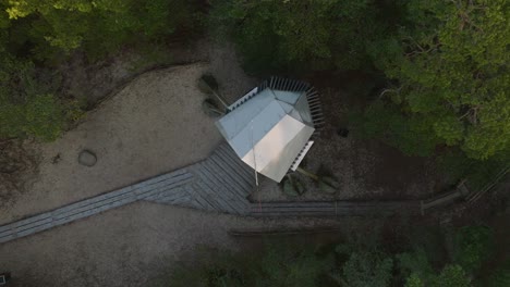vista aérea de pájaro de la moderna torre de observación en forma de barco en medio del bosque de pinos, bosque nórdico, sendero forestal, tarde soleada, luz de la hora dorada, disparo ascendente de drones