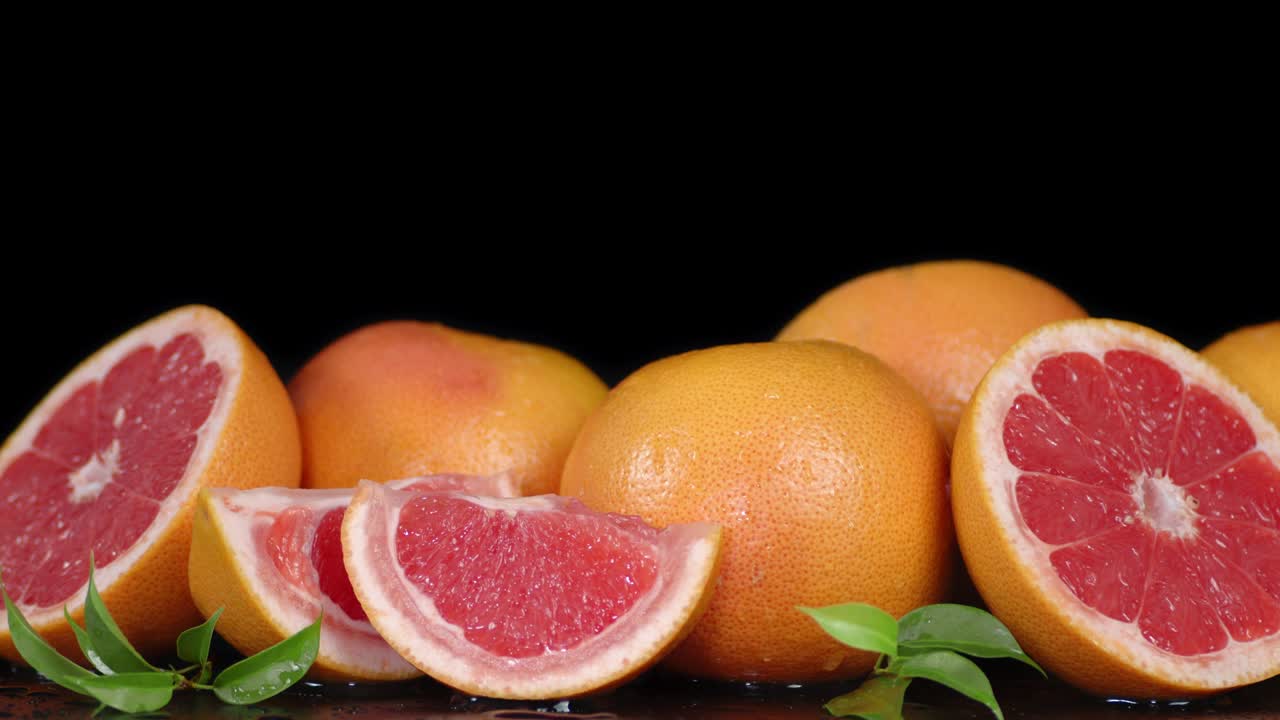 Whole and cut grapefruit with leaves slowly rotate.