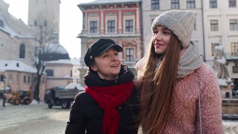 dos mujeres sonrientes hermanas turistas caminando juntas por la calle de la ciudad, pareja hablando, abrazándose