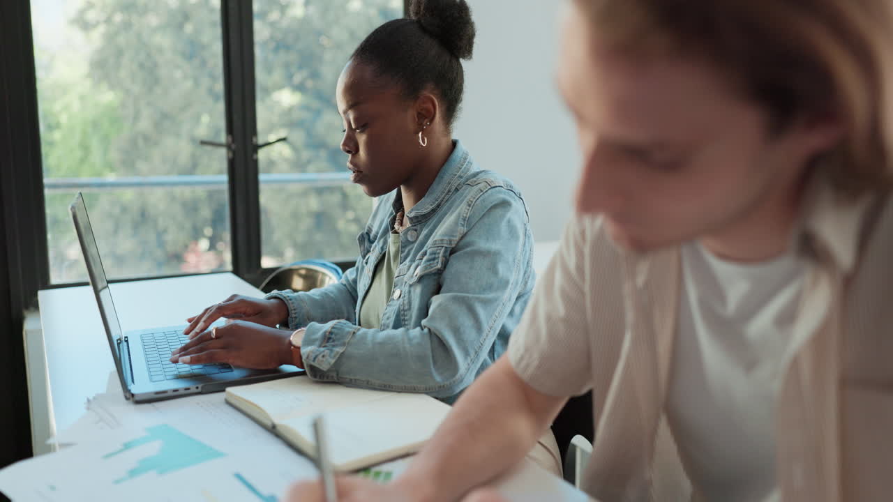 Two people working on laptops at a table