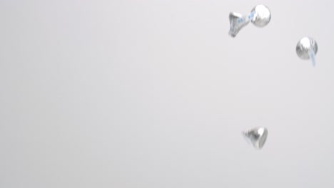 caramelos de chocolate hershey's kiss envueltos en plata lloviendo sobre fondo blanco en cámara lenta