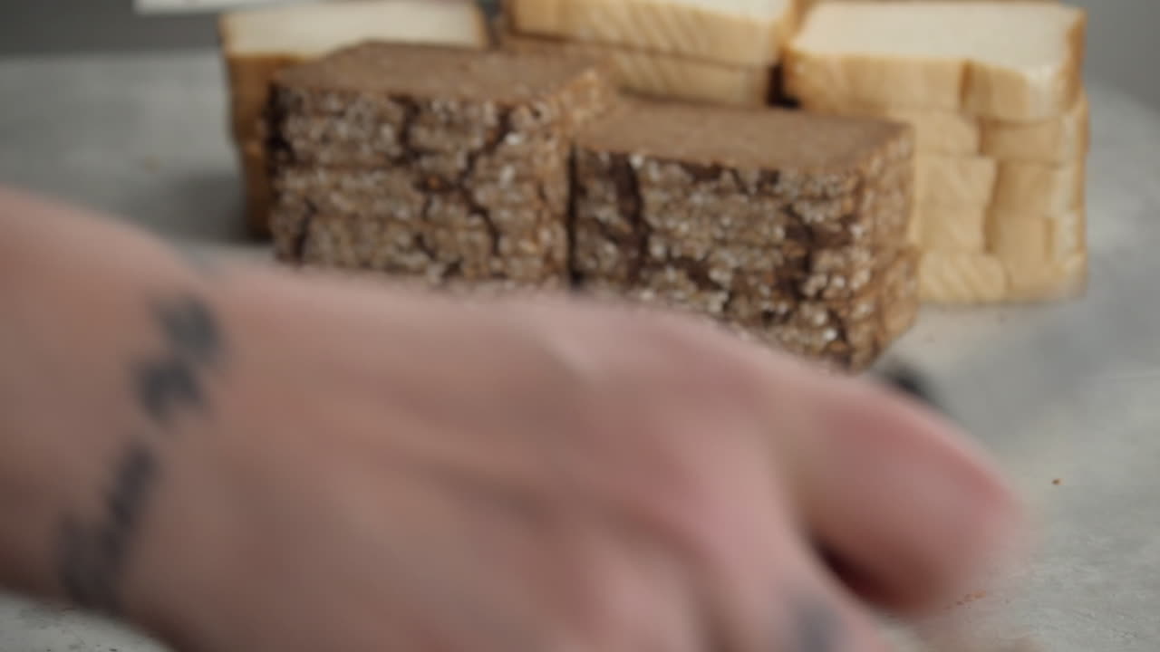 chef tatuado corta la corteza del pan integral con un cuchillo serrado