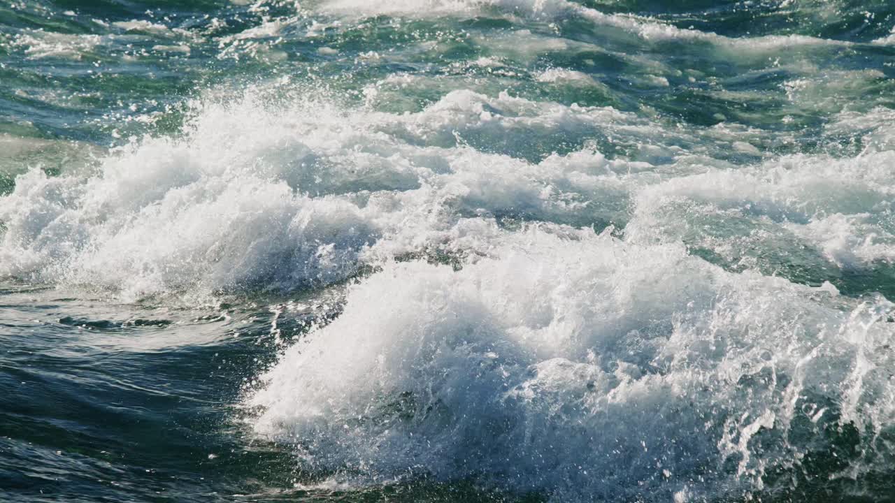 The ocean displays powerful waves crashing and splashing under the radiant sunlight. This captivating sight showcases nature's beauty and the rhythmic flow of water