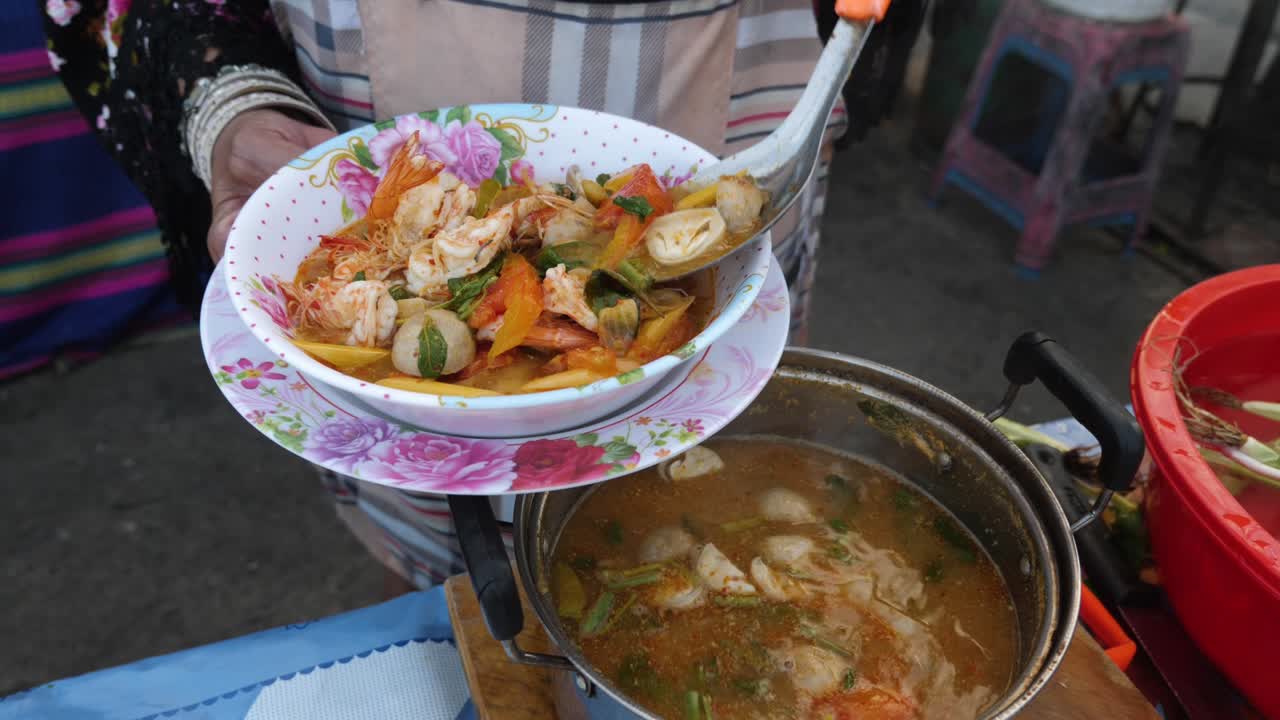 Tom Yum Kung soup being prepared by thai woman in Thailand