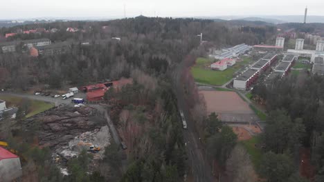 Wide-aerial-view-of-a-tram-traveling-cross-country-in-suburban-Gothenburg,-Sweden