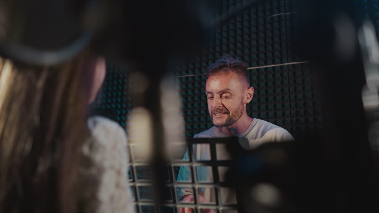 튜터는 녹음 스튜디오에서 아이와 함께 노래를 부릅니다. 프로듀서는 오디오 스튜디오에서 노래를 녹음하기 전에 작은 소녀를 준비합니다.