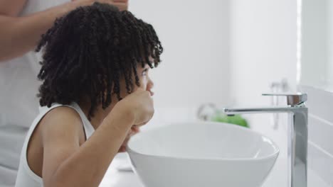 Happy-biracial-man-and-his-son-washing-teeth-in-bathroom