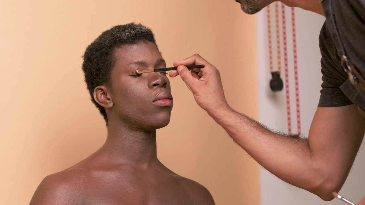 Crop visagiste filling in eyebrows of black transgender