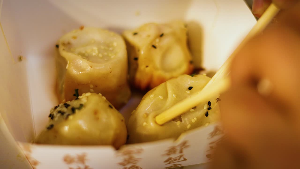Chopsticks picking delicious buns from a box