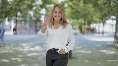 happy girl showing victory sign and smiling at camera