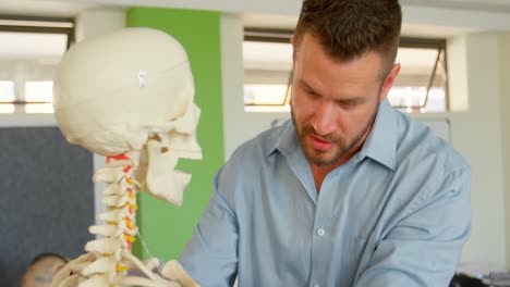 Caucasian-male-teacher-with-human-skeleton-model-in-classroom-at-school-4k