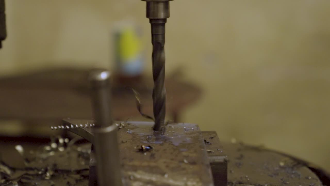Drilling tool makes hole in thick steel plate. Metal shavings fly in different directions
