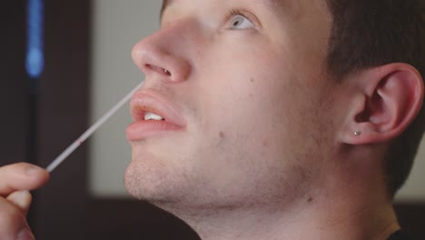 un joven en casa usa un hisopo nasal para autoevaluarse en busca de covid-19