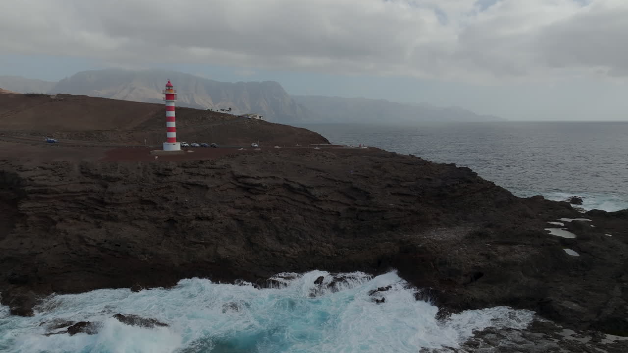faro de la sardina: vista aérea que viaja hacia el faro y donde se pueden ver las montañas, la costa y las olas que golpean