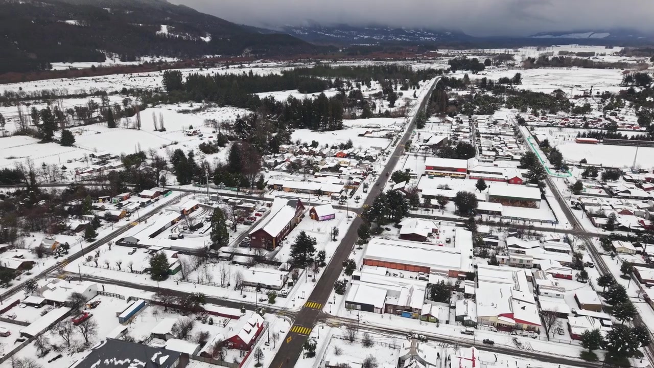 Veduta aerea sopra le strade trafficate della città di Melipeuco, tetti coperti di neve, montagne del Cile, paesaggio urbano