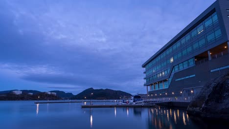 boats used by workers to commute to work are docked at office building in florvaag, norway