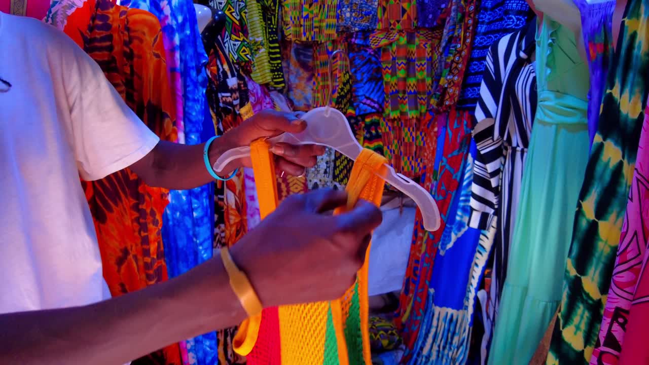 black male african seller display showcase dress and clothes inside the most famous market in Gambia