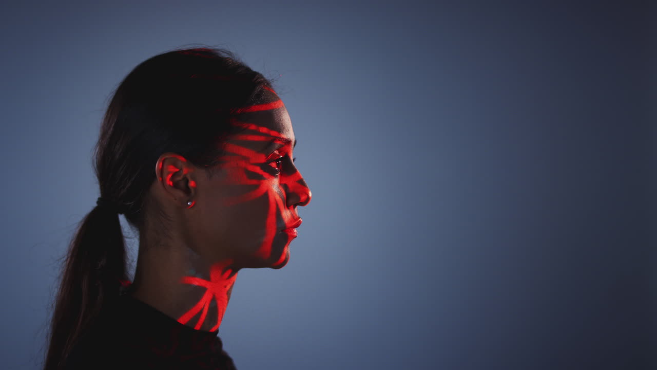 Concetto di tecnologia di riconoscimento facciale con una donna che ha una griglia rossa proiettata sul viso in uno studio.
