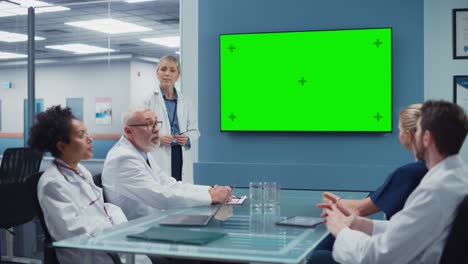 sala de reuniones del hospital: una doctora presenta la pantalla verde de chroma key a un equipo de profesionales médicos. científicos de investigación discuten el tratamiento del paciente, los medicamentos y el desarrollo de medicamentos