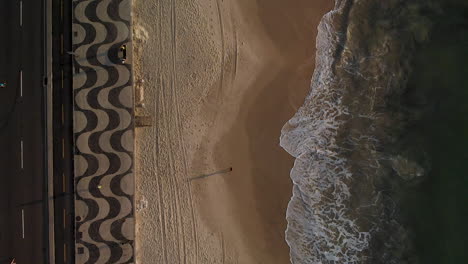 Wave-rolling-in-on-Copacabana-beach-at-sunrise-with-a-person-passing-by-causing-a-long-shadow