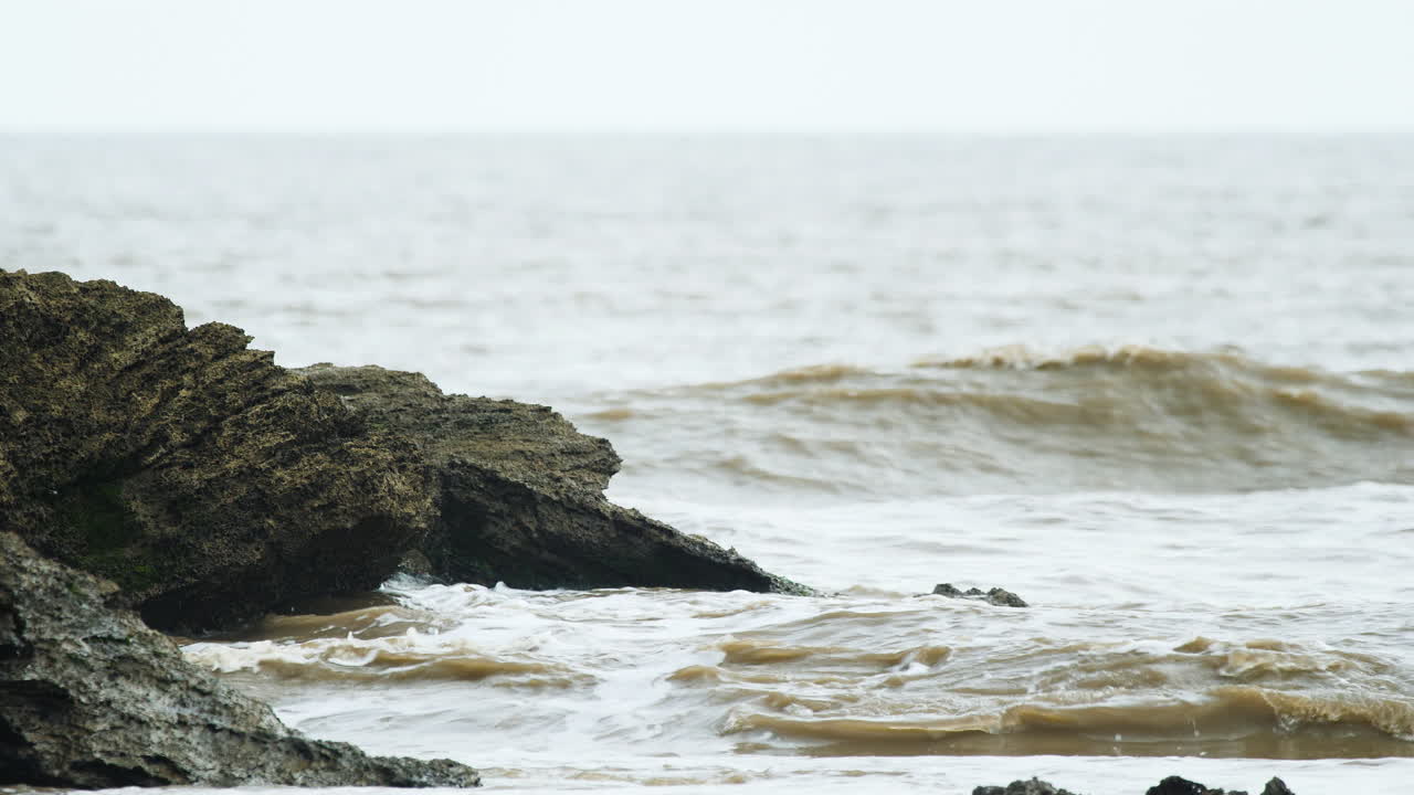 las olas rompen sobre la roca en el mar durante el comienzo de la marea alta en el mar arábigo en una tarde