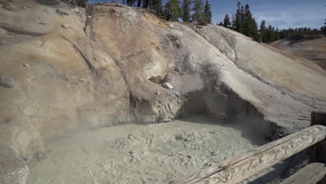 Cámara-Lenta-De-Un-Muddpot-Hirviendo-En-El-Parque-Nacional-Volcánico-Lassen-Y-Una-Valla-De-Madera-En-Primer-Plano