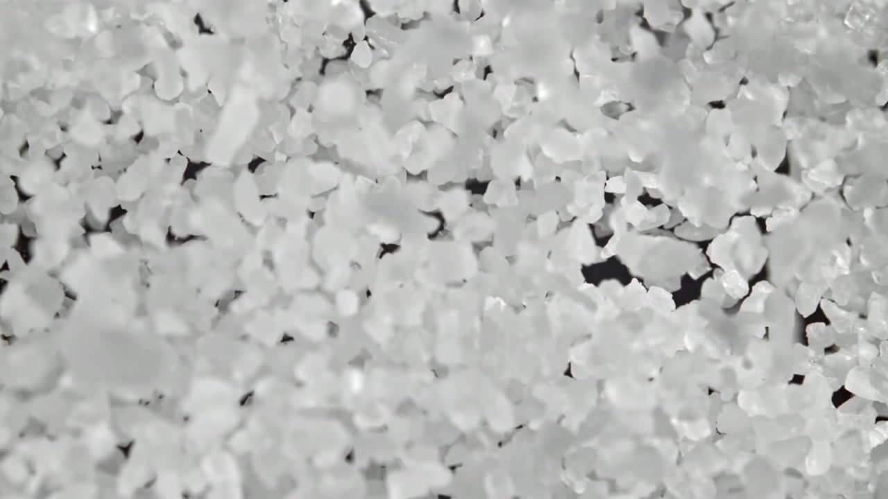 Primo piano macro di cristalli di sale bianco che cadono al rallentatore