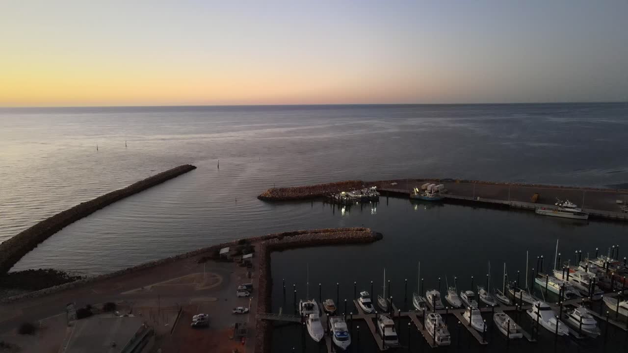 dron aéreo moviéndose hacia atrás durante el amanecer sobre el puerto de exmouth y todavía el océano