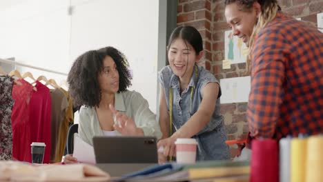 Happy-diverse-designers-using-laptop-and-discussing-work-in-fashion-design-studio-in-slow-motion