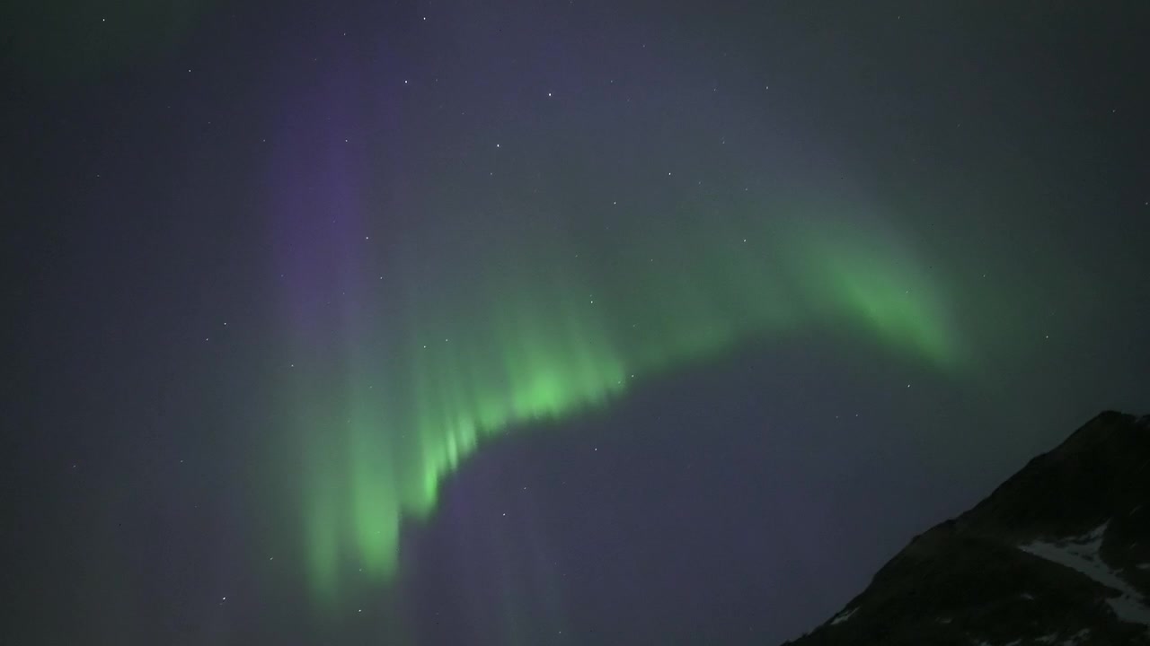 Aurora Boreale Vibrante che Danza su Montagna Innevata e Paesaggio Costiero