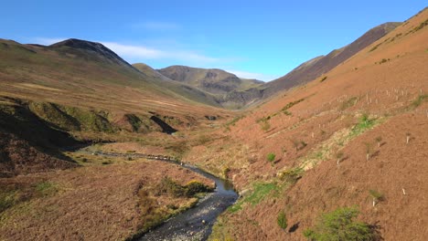 Meandering-stream-with-pan-up-showing-mountains-in-springtime-near-Force-Crag-Mine-Coledale-Beck-in-the-English-Lake-District