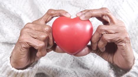 elderly hands holding a red heart