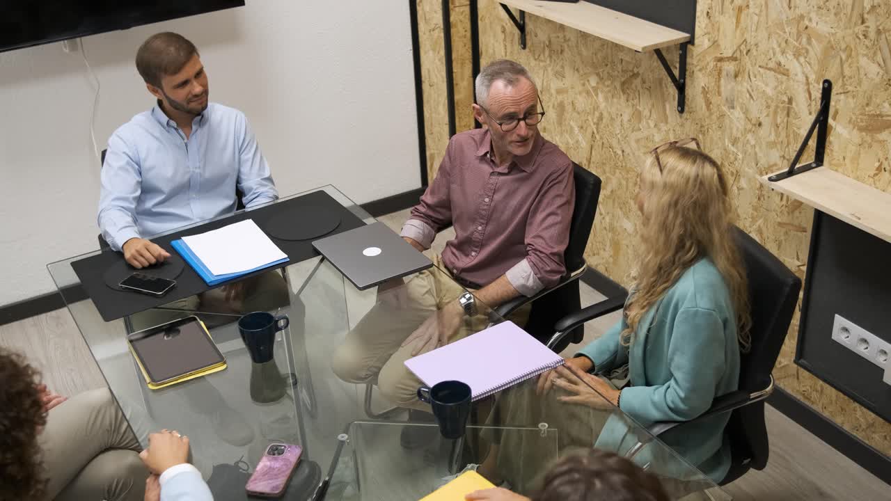 From above of business partners shaking hands during conference meeting