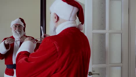 santa claus looking in mirror and put pink glasses on his eyes