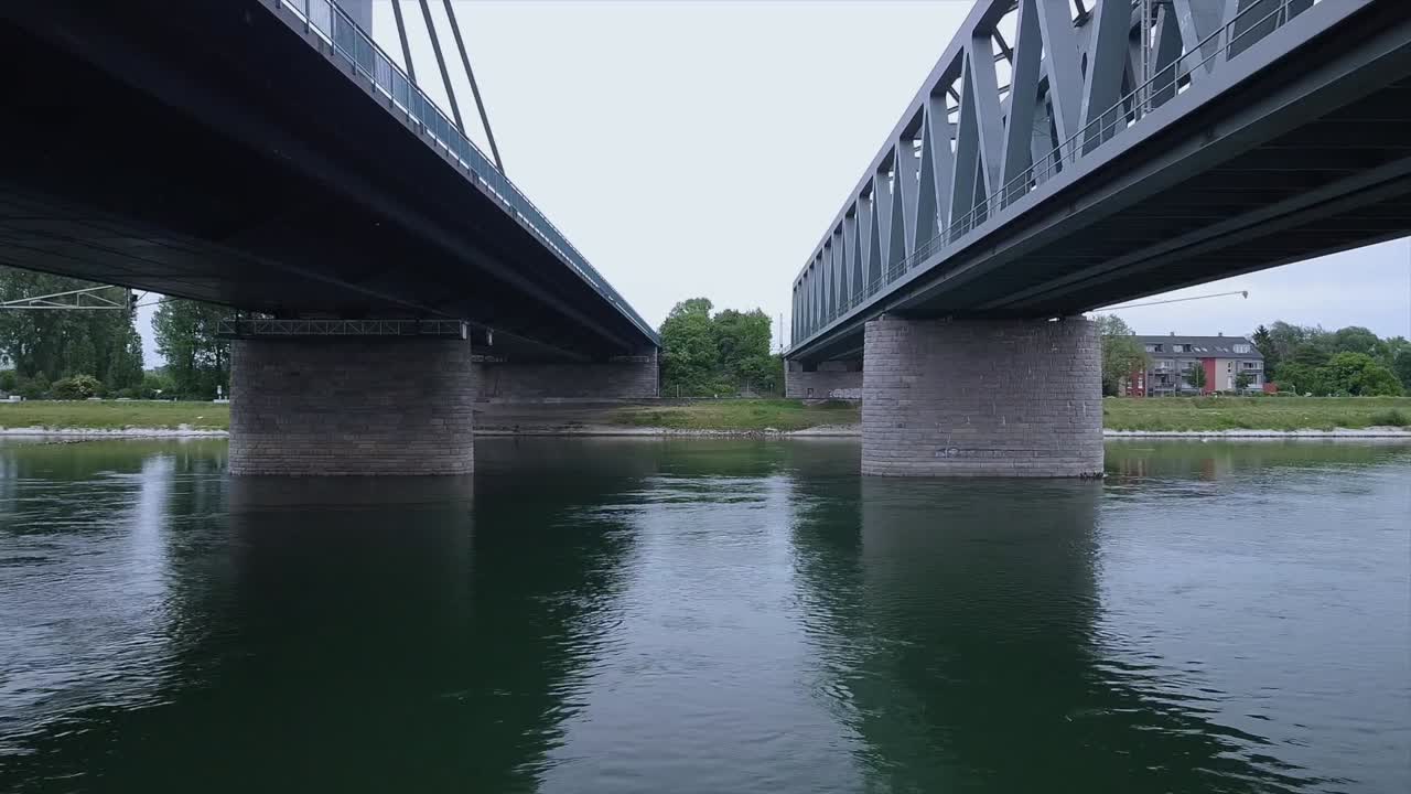 Drone flying low altitude over the whole width of the River under a railroad and an automobile bridge spanning over an important waterway in Europe