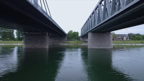 drone flying low altitude over the whole width of the river under a railroad and an automobile bridge spanning over an important waterway in europe