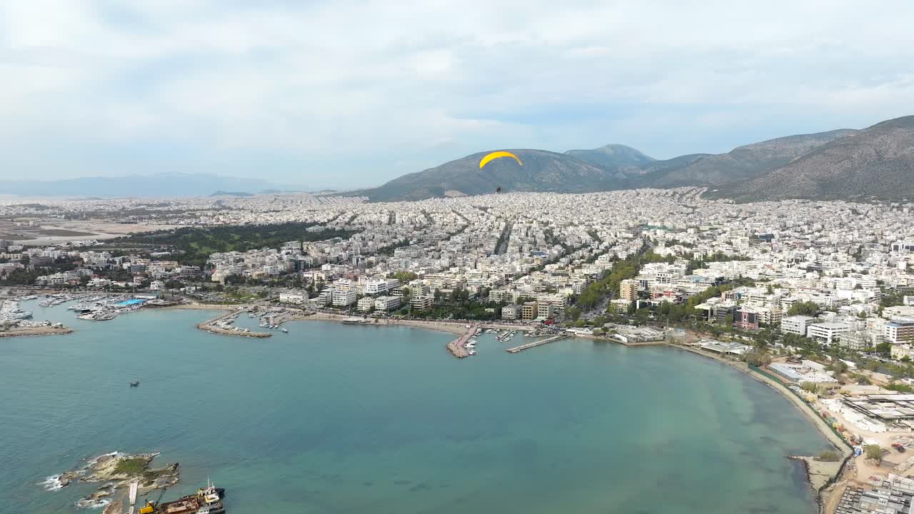 sobrevuelo de parapente de motor amarillo bahía de agua turquesa en el paisaje urbano de glyfada, atenas
