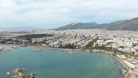 sobrevuelo de parapente de motor amarillo bahía de agua turquesa en el paisaje urbano de glyfada, atenas