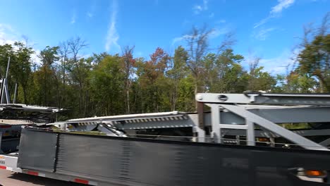 Car-carrier-truck-on-a-sunny-highway-with-trees