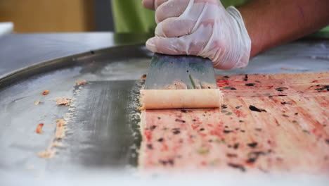 Worker-carefully-pushes-up-rolls-of-Thai-rolled-ice-cream,-slow-motion-close-up-4K