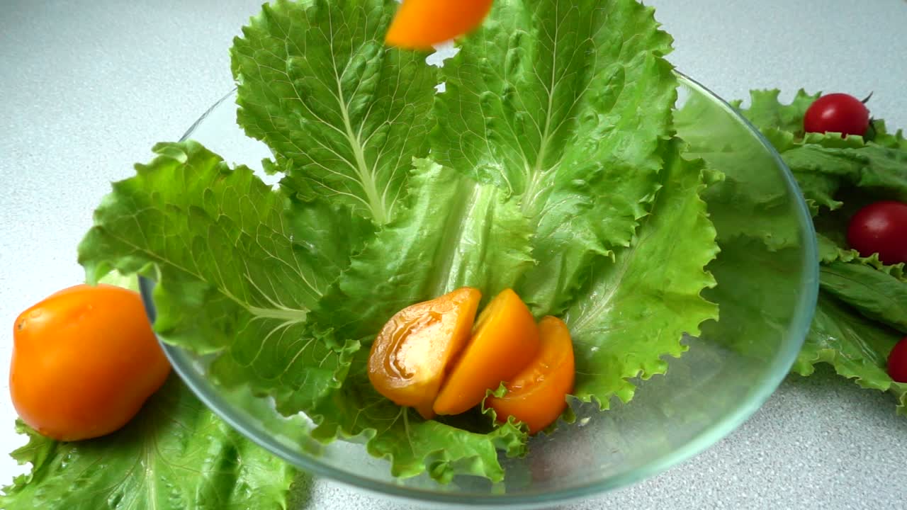 The falling tomatoes on lettuce leaves. Slow motion