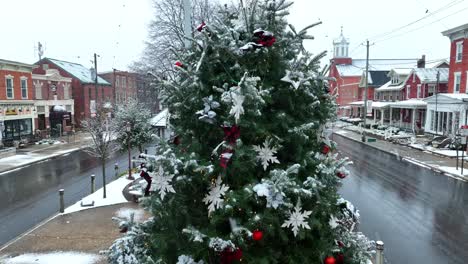 árbol de navidad en la plaza de la ciudad cubierto de nieve durante las ráfagas