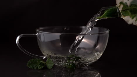 teapot pouring mint tea into glass cup