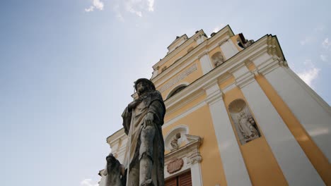 panning around a stone statue in front of an old catholic church falkenstein in, austria on a sunny summer day