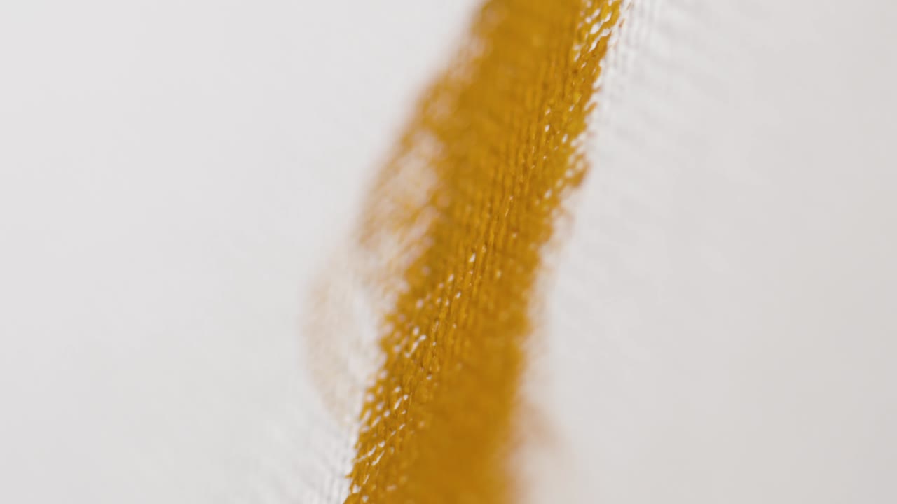 primer plano de un pincel aplicando pintura amarilla a un lienzo