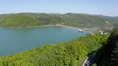 maneciu reservoir surrounded by mountain foliage with asphalt road in prahova county, muntenia, romania