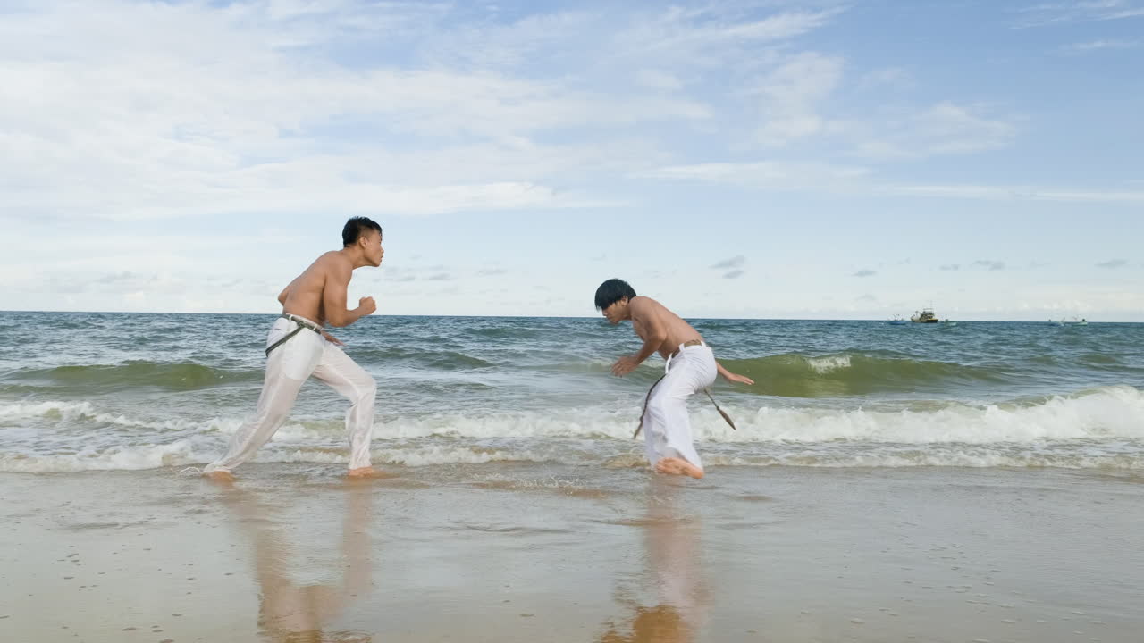dos hombres bailando capoeira en la playa